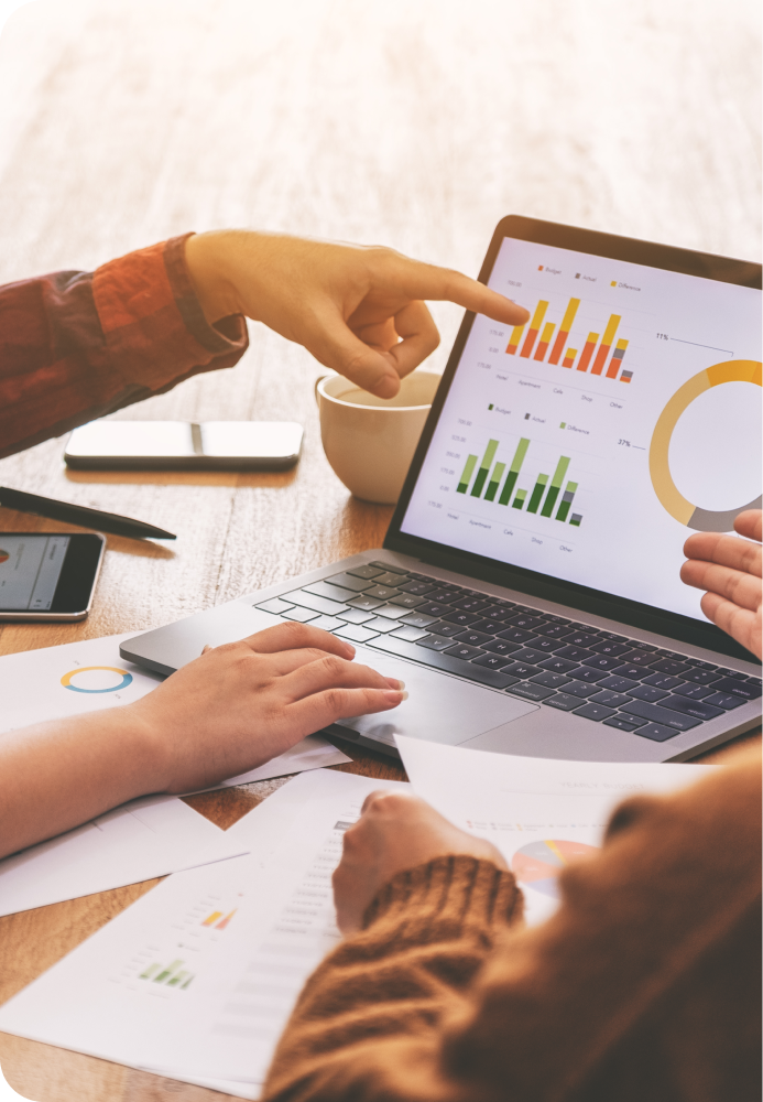 Image of people pointing to a slew of graphs on a laptop screen.